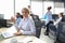 Joyful businesswoman in formalwear working on laptop in the modern office with collegues on the background