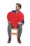 Joyful casual man holding a heart shape and looking sideways