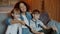 Joyful Caucasian children watching TV with African American nanny at home