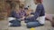 Joyful Caucasian girl teaching younger brother and sister playing a game. Happy teenager spending free time with kids at