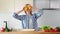 Joyful charming young girl dancing holding fresh yellow pepper on eyes during cooking healthy food