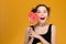 Joyful charming young woman holding bright heart shaped candy