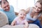 Joyful child crawling on sofa and happy parents looking at it