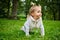 A joyful child crawls the grass in the park