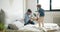 Joyful child fighting pillows with daddy having fun on bed in bedroom together