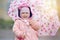 Joyful child with pink flower umbrella in the sun light after rain