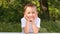 Joyful child is sitting at a table in nature and smiling.