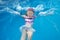 Joyful child splashing into swimming pool in summer
