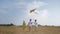 Joyful children, contented kids walking with kite in meadow during summer holidays on blue sky background, freedom