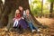 Joyful company of children sits carefree on tree in forest, a happy childhood in nature