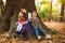 Joyful company of children sits carefree on tree in forest, a happy childhood in nature