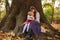 Joyful company of children sits carefree on tree in forest, a happy childhood in nature