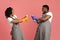 Joyful couple fooling during spring-cleaning, aiming detergent sprayers at each other