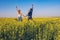 Joyful couple with open arms is jumping on the field