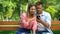 Joyful couple spending time together in park watching photos on smartphone, date
