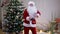 Joyful dance of happy Santa Clause in living room at Christmas tree. Front view medium shot Caucasian man in Father