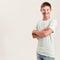 Joyful disabled boy with Down syndrome smiling at camera while posing, standing with arms crossed isolated over white