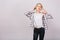 Joyful ecstatic blonde girl posing against grey background, touching big white headphones, listening her favorite music