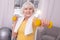 Joyful elderly woman exercising with dumbbells