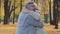 Joyful elderly woman and man in autumn park grandpa holding phone aged couple receive good news celebrating victory