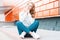 Joyful european young cheerful woman in a vintage sweater in trendy jeans in sneakers sits and dreams