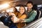 Joyful family inside car, daughter playfully steering with dad