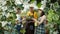 Joyful family mum granny and kid talking and laughing looking at beautiful plant in glasshouse