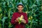 joyful Farmer agronomist looking at camera and peeling corn ear on the cob