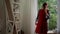 Joyful fashionable Caucasian senior woman trying on luxurious red dress in front of mirror at home. Portrait of