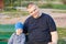 Joyful father sitting with his displeased son on a bench in the park