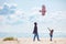 Joyful father and son, family launching the kite on sandy beach, at windy day