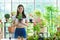 Joyful female entrepreneur florist plant seller holding a croton foliage plant pot in a floral shop