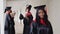 A joyful female graduate with a diploma in hand stands at the university against the background of graduates talking to