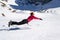 Joyful female hiker jumping on the snow, horizontally, resembling a Superman/Superwoman levitating pose, near Malaiesti hut