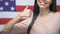 Joyful female showing thumbs up closeup on American flag background, migration