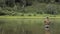 Joyful fisherman is fishing in calm river water near the shore