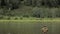 Joyful fisherman is fishing in calm river water near the shore