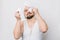 Joyful funny bearded man with white towel doing home skin care routine, using cotton pads. Dermatology treatment