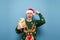 Joyful gamer with smartphone in hand isolated on blue background, emotionally happy to win with raised hand, wearing santa hat and