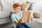 Joyful ginger boy sitting at home, reading book