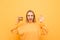 Joyful girl with a burger in her hand stands on a yellow background, shows an OK sign and looks at the camera and smiles.