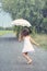 Joyful girl dance with umbrella in rain