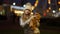 Joyful girl dancing with teddy bear in slowmo with colorful Christmas lights flashing at background on city street
