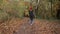 Joyful girl with dog running in autumn park