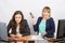 Joyful girl in the office with a phone in his hand close to the unhappy colleague