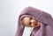 Joyful girl preschooler posing in large knitted lilac sweater, leaning aside with one hand above her head demonstrating