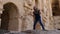 Joyful girl teenager dancing on background stony walls in ancient fortress