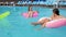 Joyful girlfriends swimming on inflatable ring and mattress in pool, summer rest of beautiful girls in swimsuits