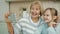 Joyful granny and little girl taking selfie with smartphone camera in cozy modern kitchen