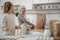 Joyful granny making pastry with her granddaughter in kitchen